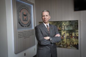 Dean Brian L. Crabtree next to college seal