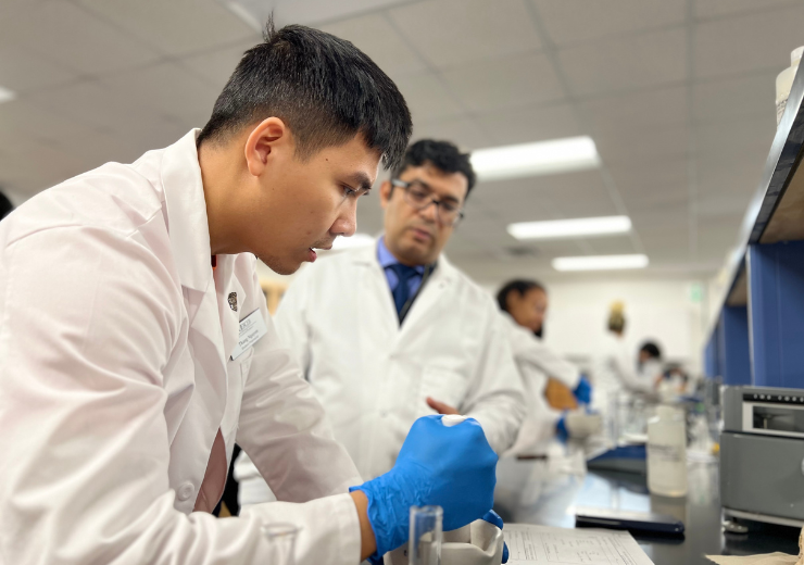 a student working in the compounding lab as a professor looks on.