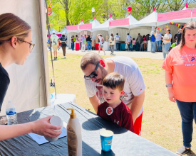 A student teaching a young child and an adult a science experiment