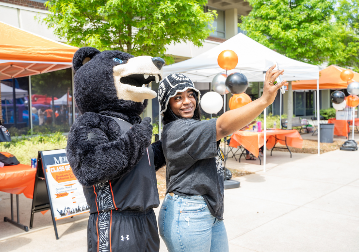 a student taking a selfie with Toby, the Mercer mascot