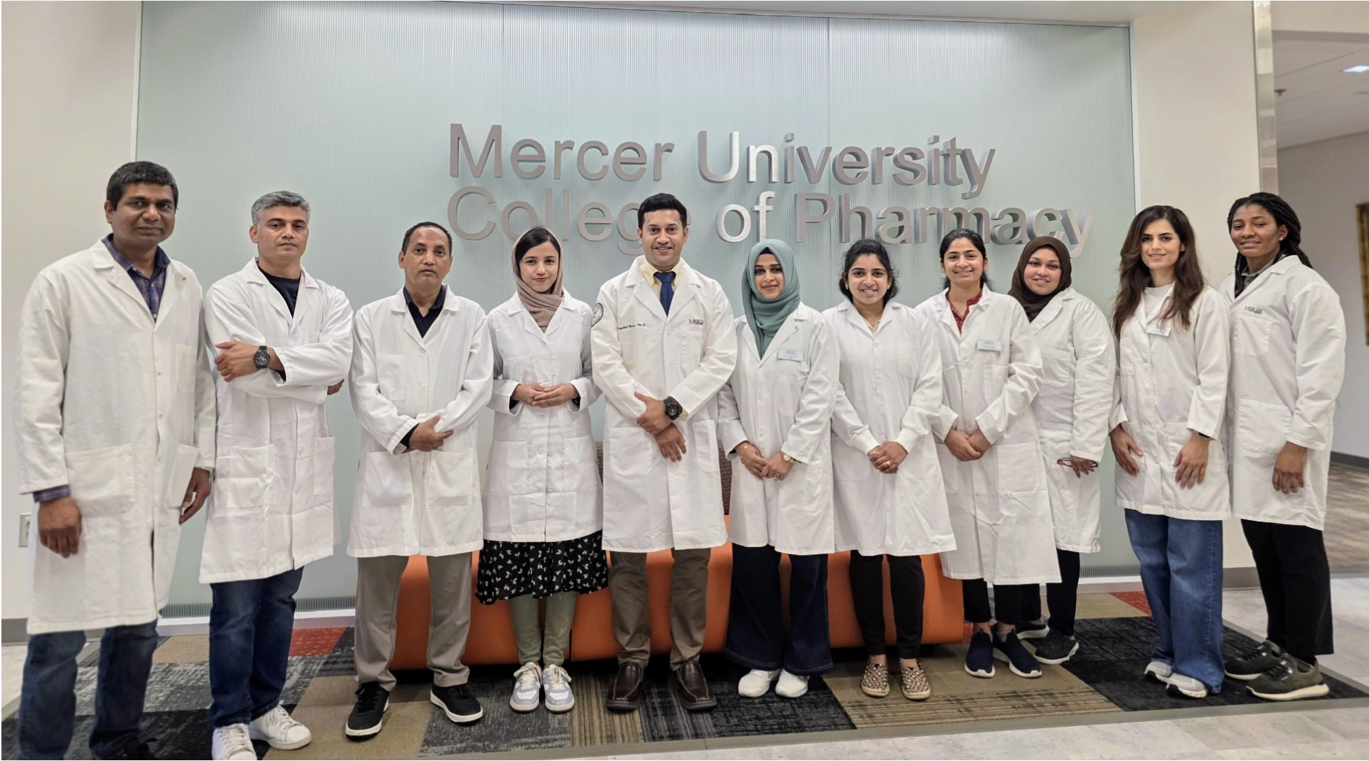 a group photo of students and faculty in a white coat.